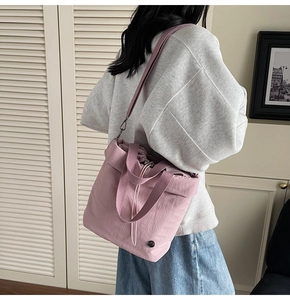 Detail of mauve bucket bag featuring drawstring closure and textured nylon fabric