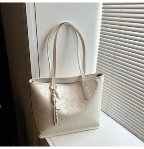 Détail d'un cabas blanc cassé avec motifs d'ours embossés et un pendentif assorti