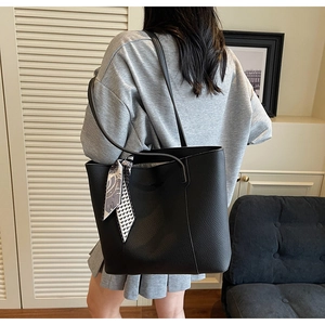 Close-up of black pebbled leather tote bag featuring a geometric silk scarf on the handle