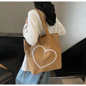 Détail du sac cabas en toile kaki avec écusson cœur blanc et petit bouton cœur métallique