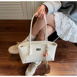 Detail of white PU tote bag with pebbled leather texture and heart charm accessory
