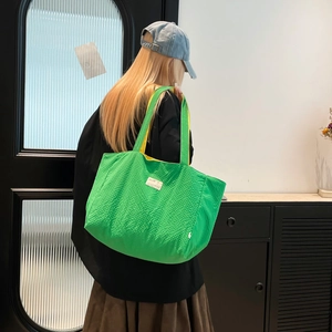 Détail du sac cabas matelassé vert avec doublure jaune contrastée et bandoulières