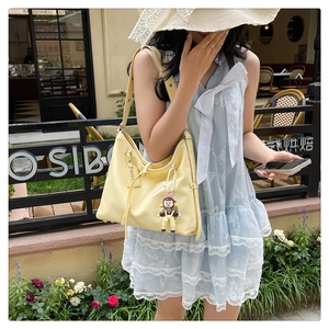 Close-up of yellow hobo shoulder bag with cute plush doll charm and matching hangtag