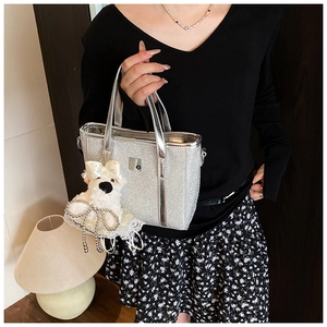 Detail of silver sequin bucket bag with cute white plush dog pendant in lifestyle setting