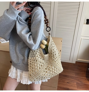 Detail of hand-woven straw tote with vintage brown wooden bead handles and floral accent