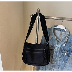Detail of black canvas crossbody bag with multi-pocket design and adjustable strap