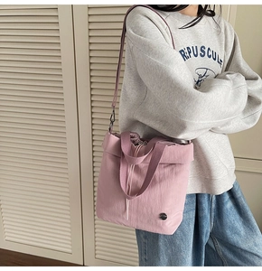 Detail of dust pink nylon bucket bag featuring drawstring closure and metallic logo