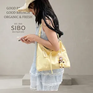 Detail of light yellow hobo bag with fringe tassel and cute cartoon doll charm