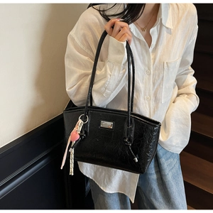Detail of glossy black pleated underarm bag with silver logo and heart charm