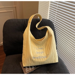 Detail of light yellow tote with pleated texture and Live laugh love & bread embroidery