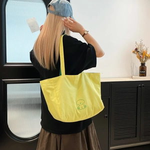Détail du sac cabas en toile jaune avec broderie de chiot vert et bandoulière de transport