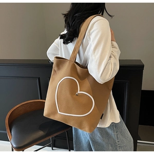 Vue latérale d'un grand sac cabas en toile caramel avec cœur brodé et détail métallique