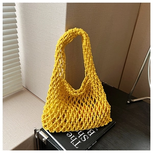 Detailed close-up of hollow yellow crochet knit handbag with integrated woven handle