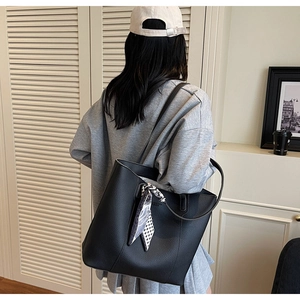 Detail of large black tote bag with lychee texture and stylish patterned silk scarf on handle