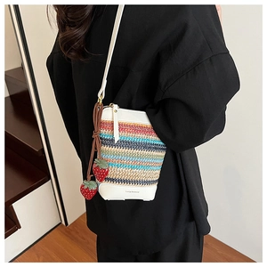 Detail of colorful rainbow woven crossbody bag with strawberry charms and leather base
