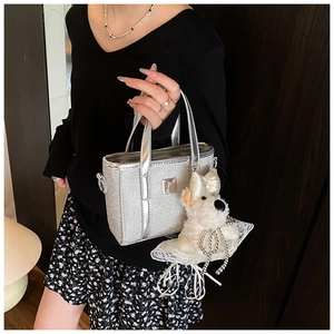 Close-up of silver glitter bucket bag with a cute white plush puppy pendant charm