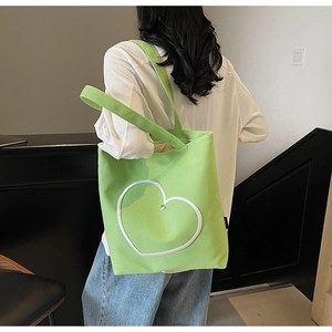 Grand sac cabas en toile vert herbe avec motif cœur, porté à l'épaule par un mannequin
