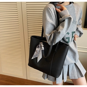 Close-up of black litchi pattern leather tote bag with stylish printed scarf handle