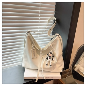 Detail of white large-capacity shoulder bag with pearl chain and cartoon charm accessory