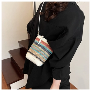 Détail du sac seau en paille arc-en-ciel avec bandoulière en cuir blanc et base logo