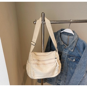 Detail of off-white canvas tote showing triple zippers and side water bottle pocket