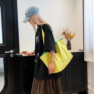 Détail du sac cabas en toile jaune avec logo de chiot vert et doublure contrastée