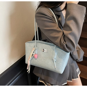 Close-up of light blue leather tote bag with litchi texture and pink heart charm