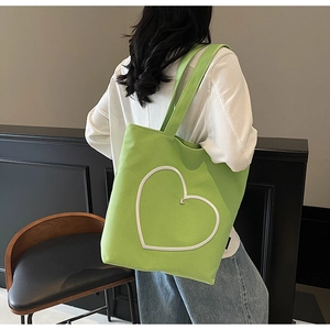 Vue arrière d'un mannequin portant le sac cabas en toile vert néon avec cœur brodé
