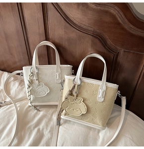Détail des motifs de dessins animés gaufrés sur le petit sac cabas en cuir blanc et jaune