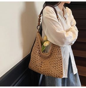 Detail of hand-woven straw tote bag with wooden bead handle and tulip decoration