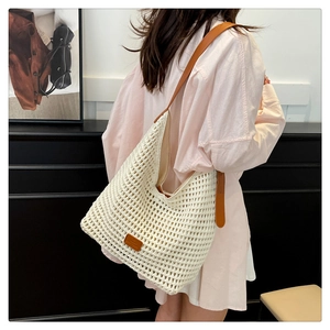 Detail of woven tote bag with brown leather strap and logo patch on model