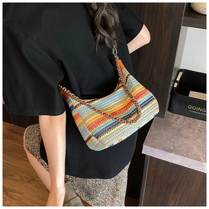 Detail view of colorful striped woven crossbody bag with metal chain strap and leather accents