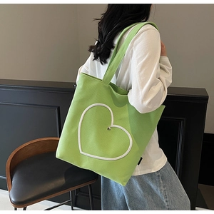 Détail du sac fourre-tout en toile verte avec motif cœur blanc et étiquette de marque