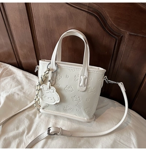 Détail du sac cabas blanc avec gaufrage de chien dessin animé et breloque chien mignonne