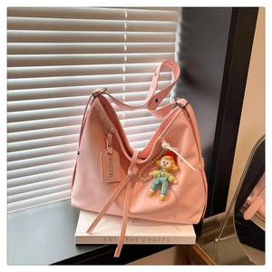 Detail of pink shoulder bag with adjustable strap and decorative clown charm on a window sill