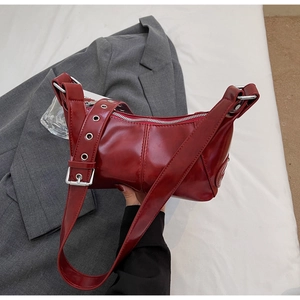 Dettaglio borsa bordeaux in pelle lucida con tracolla con occhielli e zip metallica