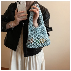 Close-up of light blue hollow knit tote bag held by a person featuring woven texture
