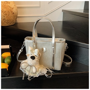 Macro view of silver sequin bucket bag featuring a cute plush dog pendant and strap