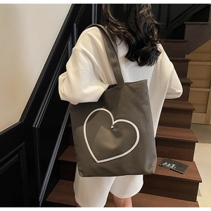 Détail d'un sac cabas en toile gris anthracite avec un motif de cœur brodé blanc
