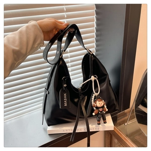 Close-up of black PU leather shoulder bag with MASHK tag and hoodie figure charm
