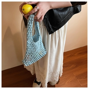 Close-up of light blue hollow knit tote bag showing handmade rope mesh texture and fruit