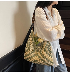 Detail of woven tote bag featuring green geometric patterns and wooden bead handle