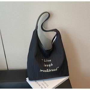 Close-up of black pleated tote bag fabric with Live Laugh Love & Bread embroidery