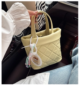 Detailed shot of yellow quilted handbag with Capybara charm inside a car setting