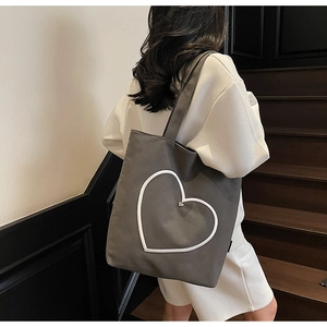 Détail du sac fourre-tout en toile grise avec couture cœur blanc et rivet en métal