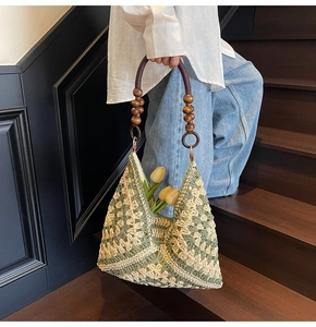 Detail of bohemian crochet tote with green floral patterns and brown wooden bead handles
