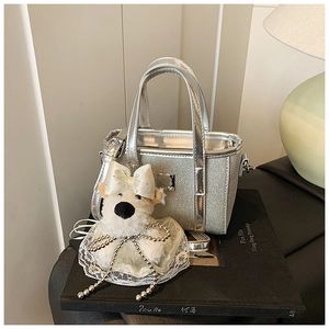 Detail of silver sequin mini bucket bag with cute white plush dog charm on a book