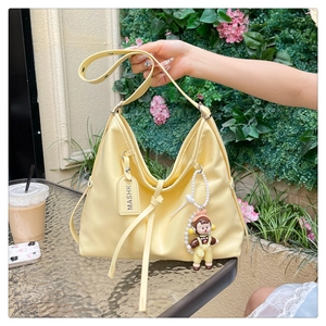 Detail view of the pale yellow tote bag with adjustable strap and cute cartoon pendant