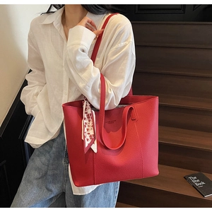 Close-up of a red lychee textured leather tote bag with heart pattern scarf detail