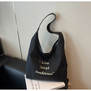 Detailed macro view of the black pleated fabric and printed slogan on this large tote bag